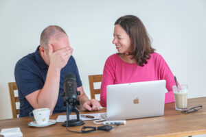 Two people working together at a laptop, one looking at each other, illustrating different perspectives on cooperation or resistance.